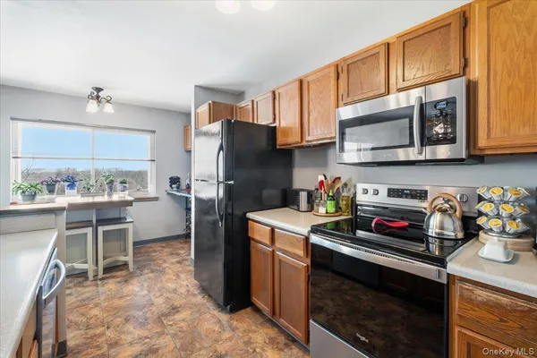 a kitchen with stainless steel appliances a stove microwave refrigerator cabinets and chairs