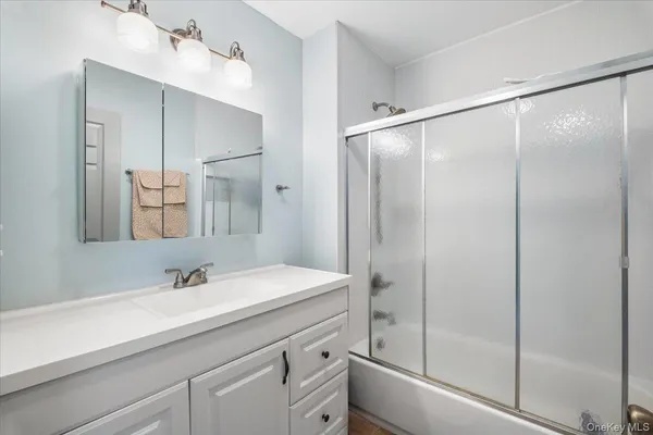 a bathroom with a shower sink vanity and mirror