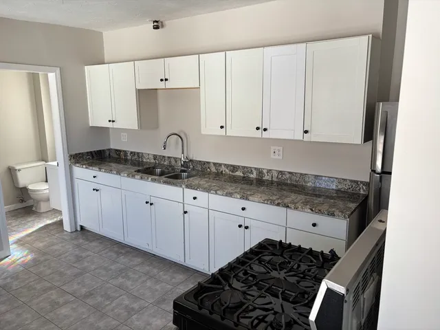 a kitchen with granite countertop a stove sink and cabinets