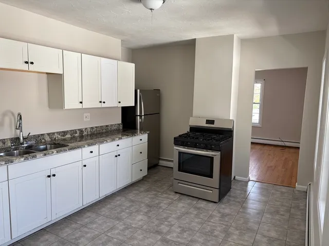 a kitchen with granite countertop white cabinets and stainless steel appliances