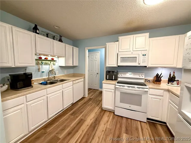a kitchen with white cabinets appliances and a sink