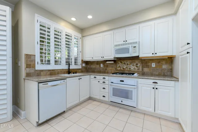 a kitchen with white cabinets a sink stove and refrigerator