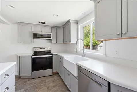 a kitchen with kitchen island granite countertop a sink appliances and cabinets
