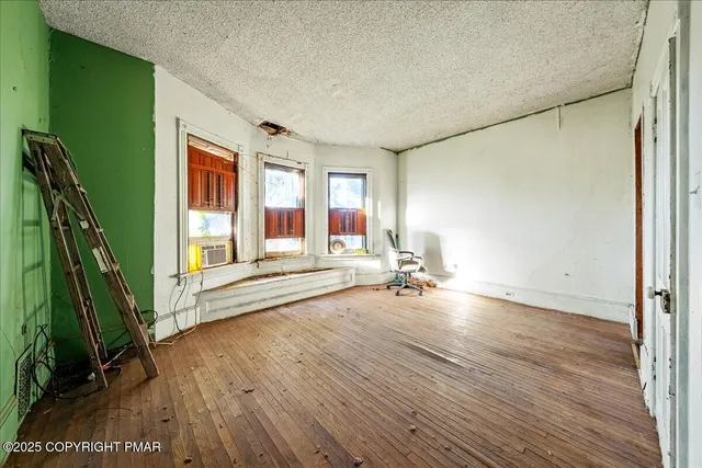 a view of empty room with wooden floor and wall