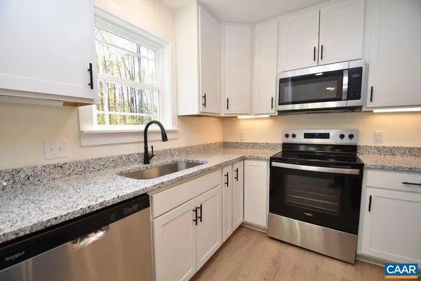 a kitchen with granite countertop a sink and a stove top oven with dishwasher