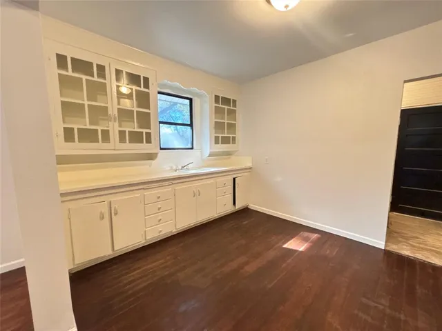 a view of an empty room with wooden floor and cabinet