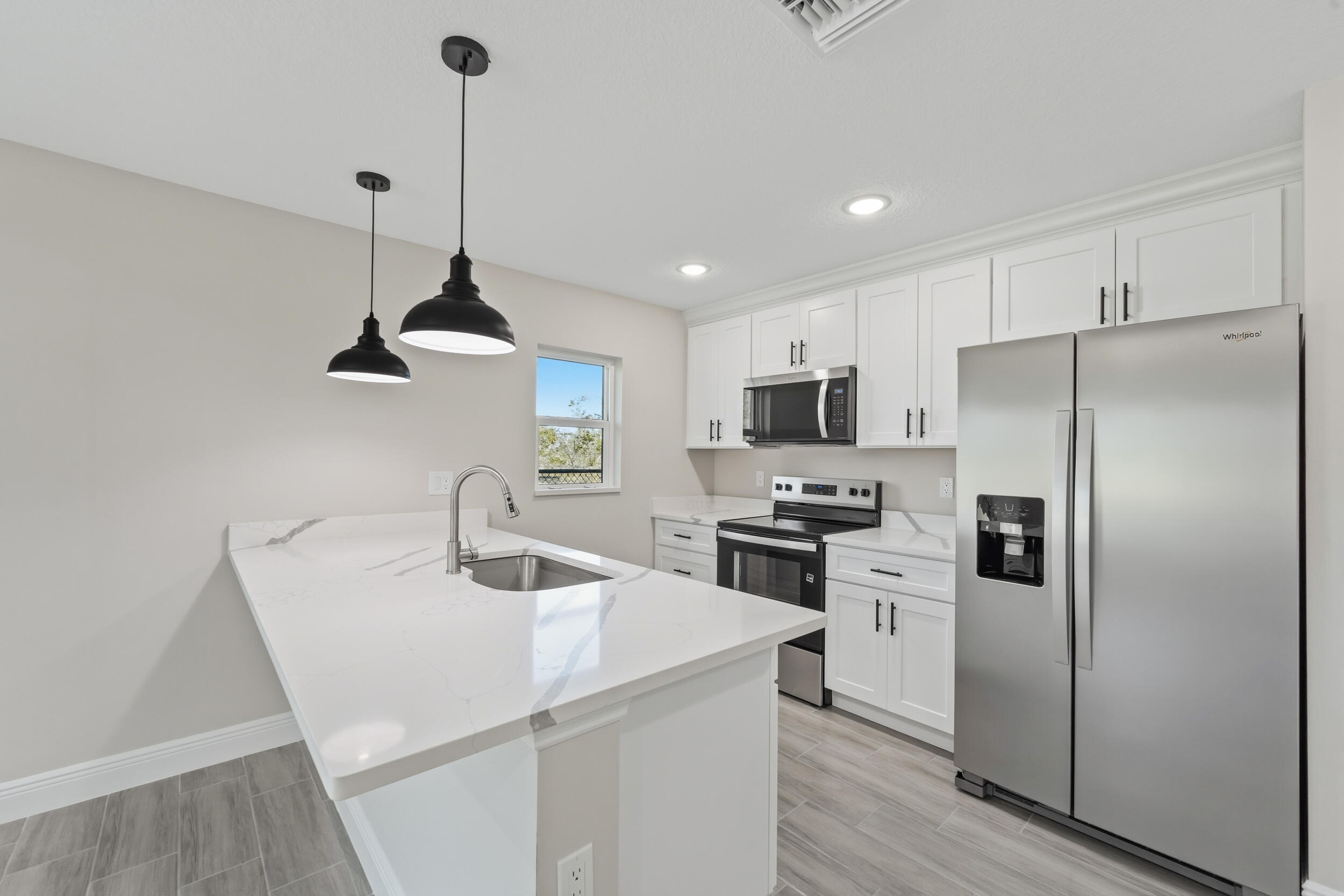 4335 Southwest 15th Way Okeechobee, FL 34974 - Photo 7 of 33 a kitchen with stainless steel appliances a refrigerator a sink a stove a microwave a center island and cabinets