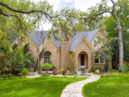 a front view of a house with a garden and trees