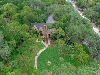 an aerial view of residential house with outdoor space and trees all around
