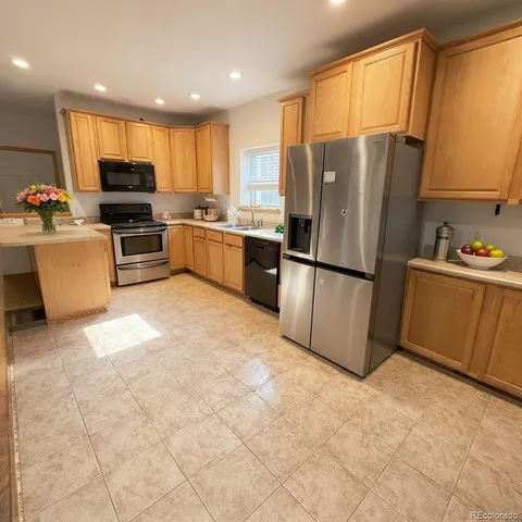 a kitchen with granite countertop a refrigerator and a stove top oven