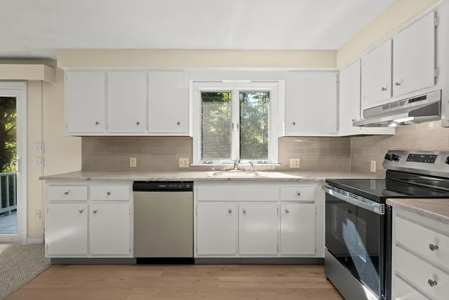 a kitchen with granite countertop white cabinets and stainless steel appliances