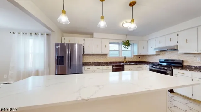 a kitchen with stainless steel appliances granite countertop a refrigerator a sink and a stove