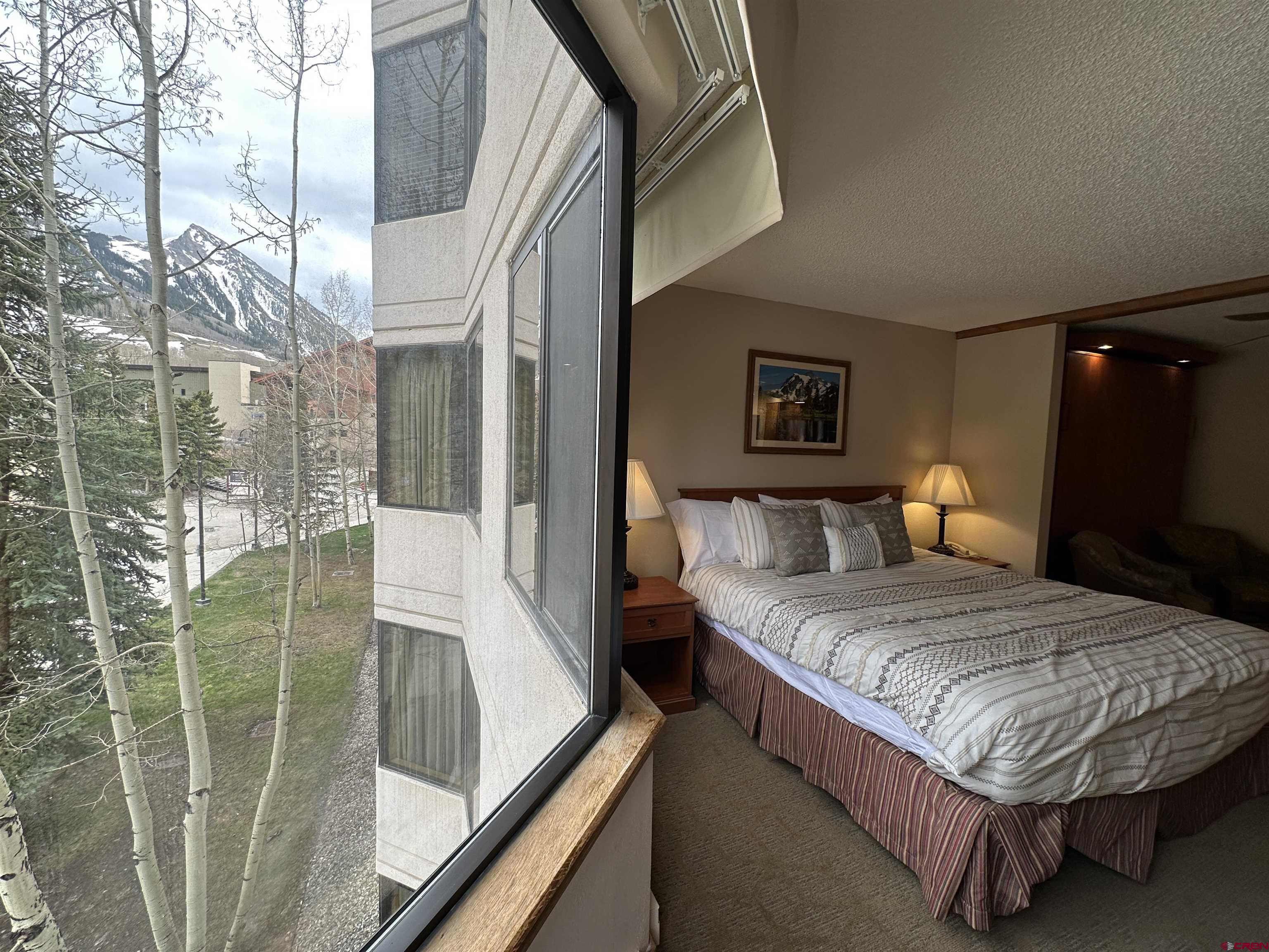 6 Emmons Road, Unit 317 Crested Butte, CO 81225 - Photo 6 of 19 a bedroom with a bed and lamp with window