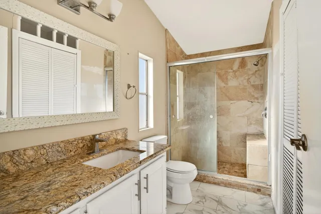 a bathroom with a granite countertop sink a toilet and shower