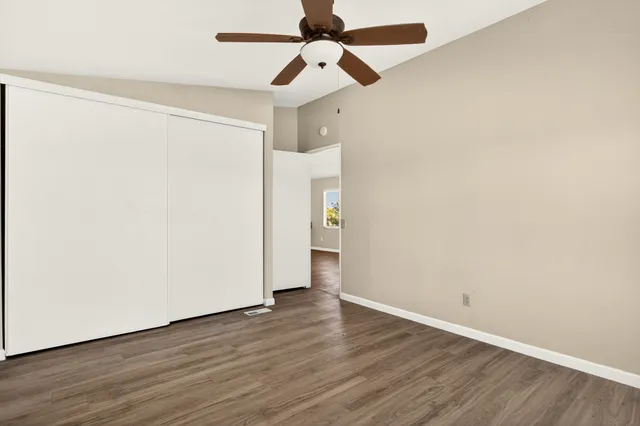 an empty room with wooden floor ceiling fan and a ceiling fan