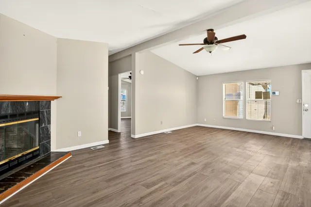 a view of empty room with wooden floor and fireplace