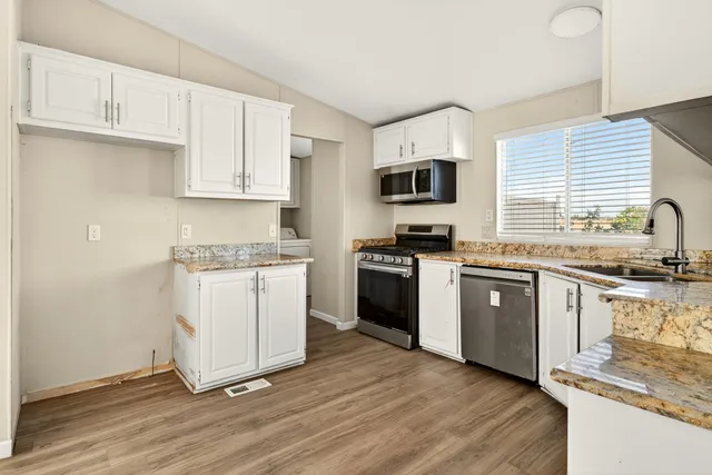 a kitchen with granite countertop white cabinets and appliances