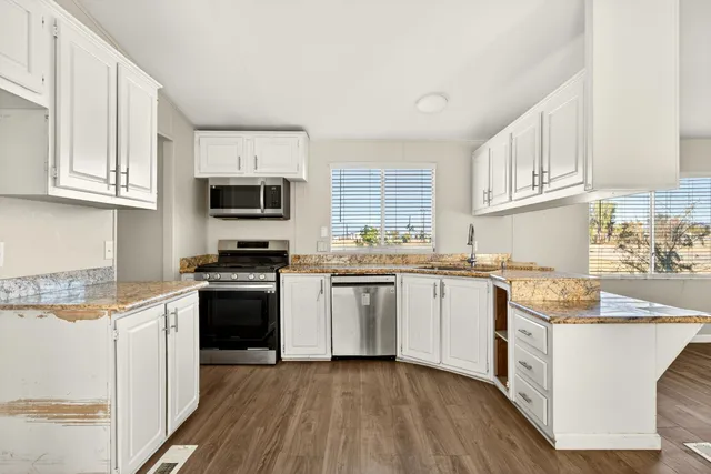 a kitchen with granite countertop white cabinets sink and stainless steel appliances