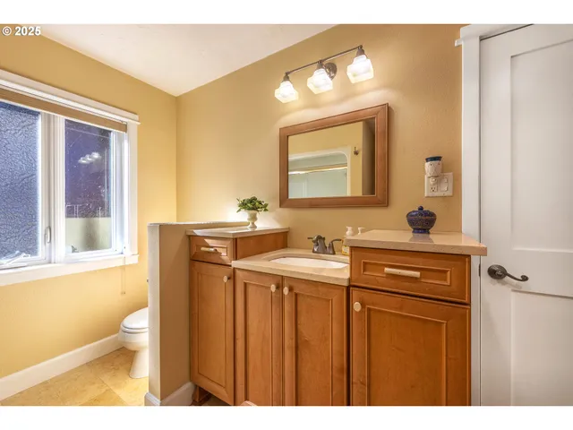 a bathroom with a toilet a sink a mirror and a window