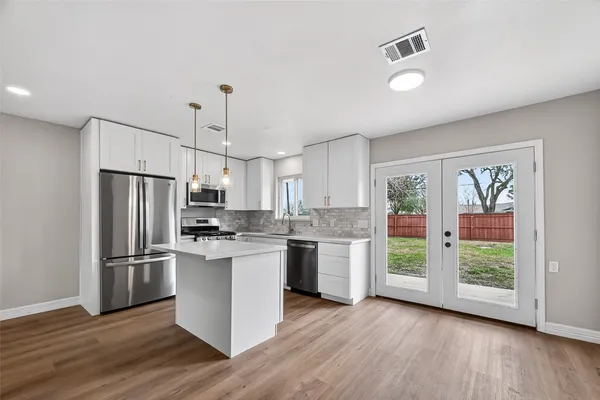 a kitchen with kitchen island wooden floor appliances and counter space