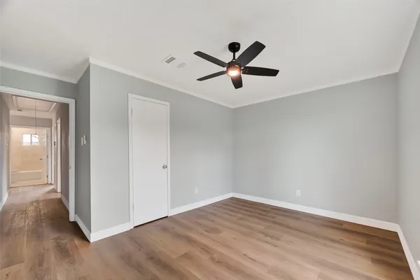 an empty room with wooden floor and ceiling fan