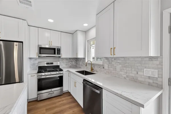 a kitchen with white cabinets stainless steel appliances and a sink