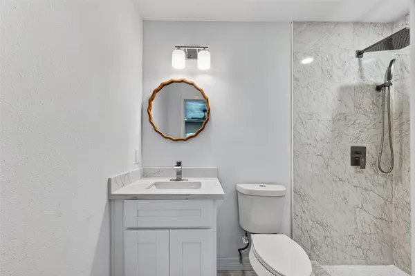 a bathroom with a toilet sink vanity and mirror