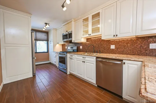 a kitchen with stainless steel appliances granite countertop wooden cabinets a sink and dishwasher a stove with wooden floors