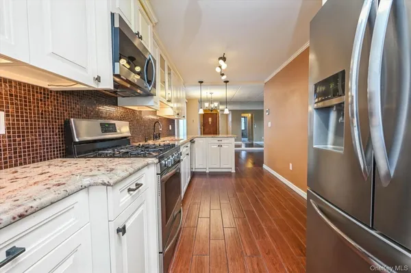 a kitchen with stainless steel appliances granite countertop a refrigerator a stove and a wooden floors
