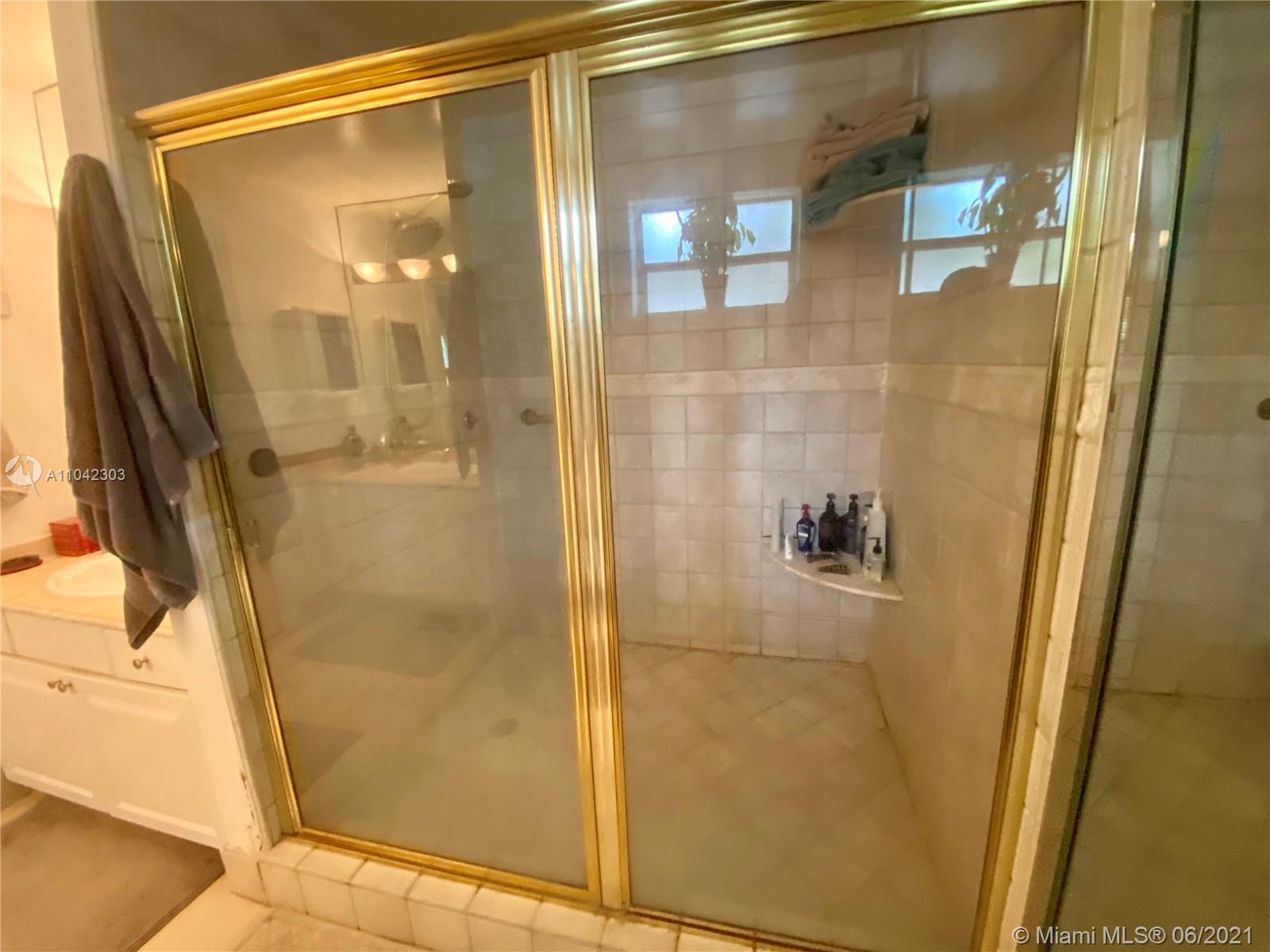 8926 Emerson Avenue Surfside, FL 33154 - Photo 13 of 18 a bathroom with a glass shower door and mirror
