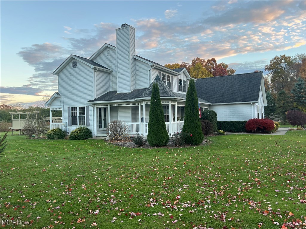 Back of property with a yard, a chimney, and a porch