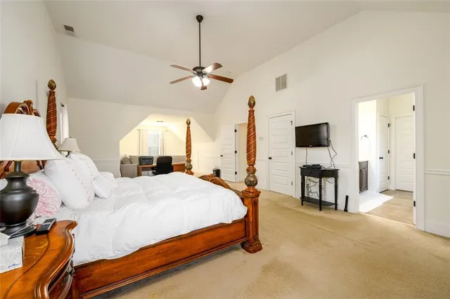 a spacious bedroom with a bed and a flat screen tv