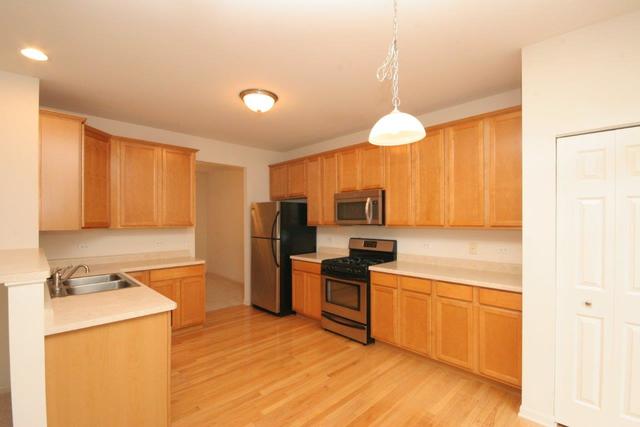 216 Longview Drive Elgin, IL 60124 - Photo 5 of 20 a kitchen with a refrigerator a stove top oven a sink and dishwasher with wooden floor