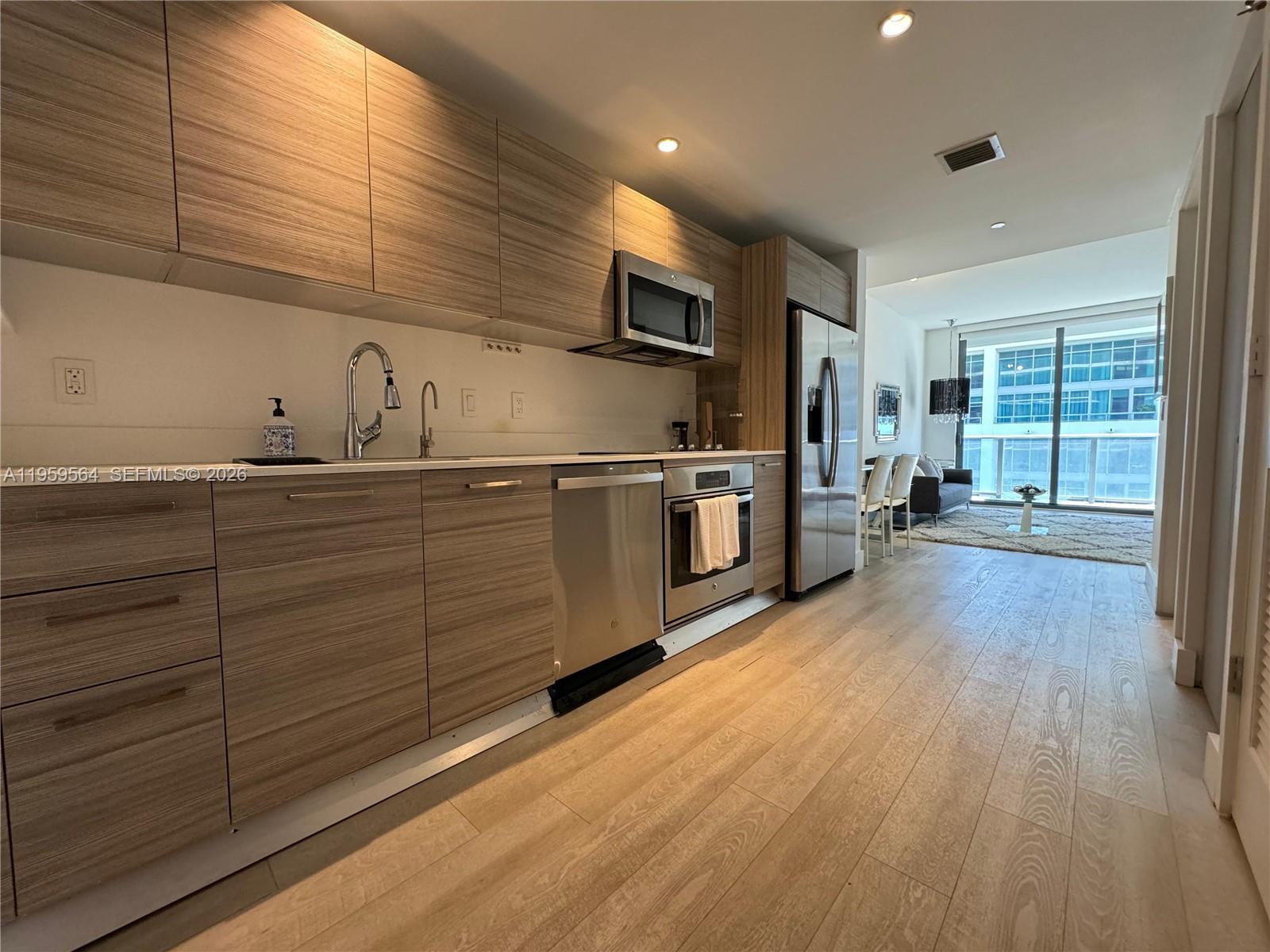 121 Northeast 34th Street, Unit L401 Miami, FL 33137 - Photo 6 of 37 a kitchen with stainless steel appliances granite countertop a sink a stove and cabinets