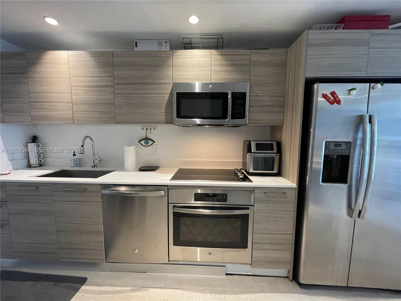 121 Northeast 34th Street, Unit L401 Miami, FL 33137 - Photo 8 of 37 a kitchen with stainless steel appliances a stove microwave and refrigerator