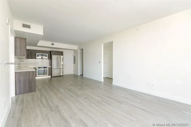 a view of a kitchen with wooden floor and a refrigerator