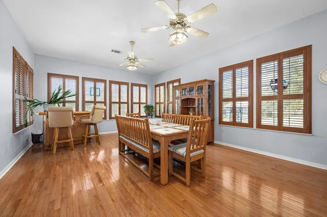 a dining room with wooden floor a chandelier a wooden table and chairs