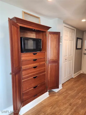 a view of kitchen with stainless steel appliances wooden floor and cabinet