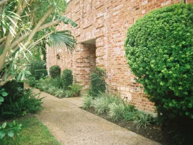 a view of a building with a yard and large trees