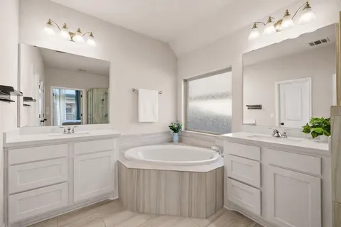 a bathroom with a sink double vanity mirror and a bathtub