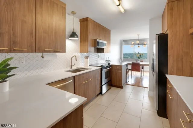 a kitchen with stainless steel appliances a sink dishwasher stove refrigerator and cabinets