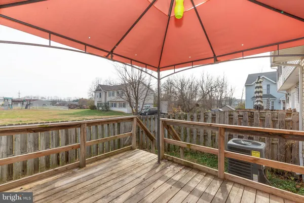 a view of a balcony with wooden floor and fence next to a yard