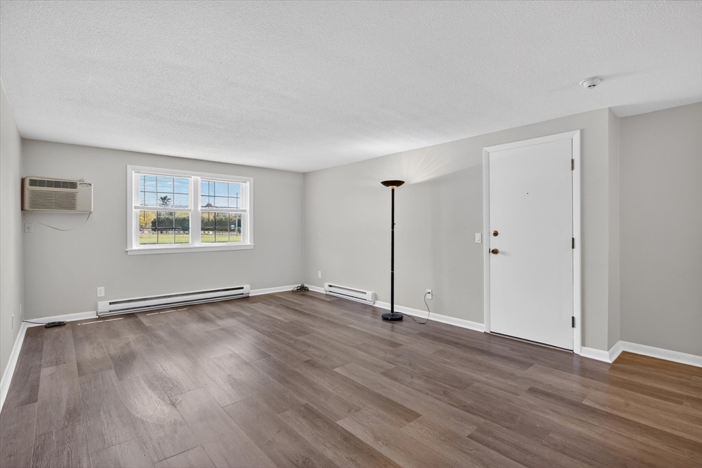 91 Pleasant Street, Unit A6 Medfield, MA 02052 - Photo 6 of 17 a view of an empty room with wooden floor and a window