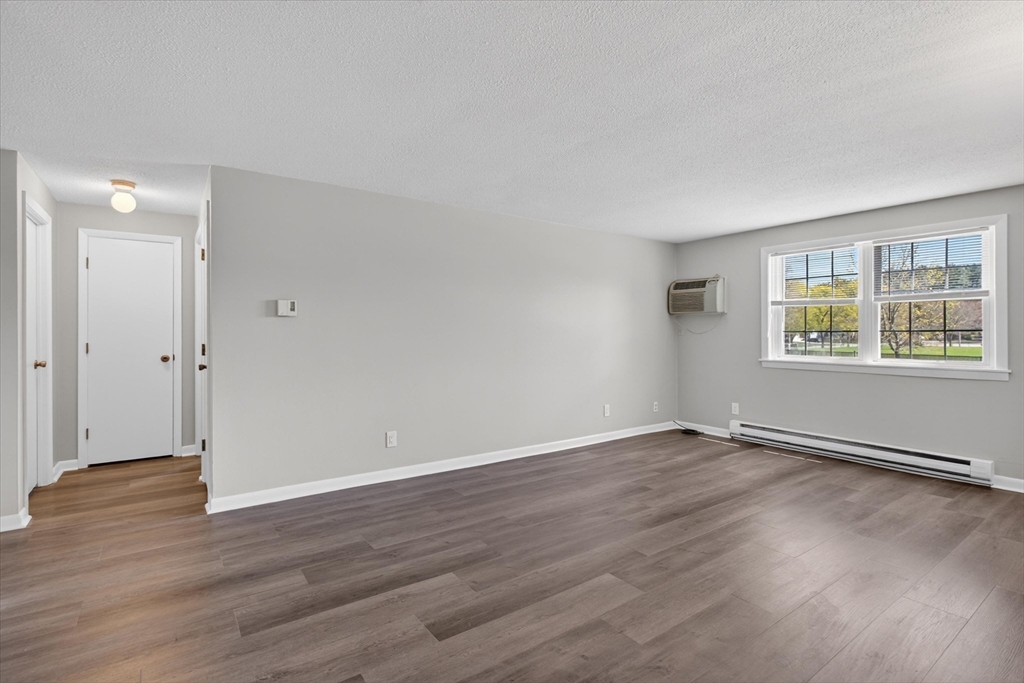 91 Pleasant Street, Unit A6 Medfield, MA 02052 - Photo 7 of 17 an empty room with wooden floor and windows