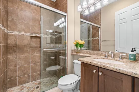 a bathroom with a granite countertop sink a toilet a mirror and shower