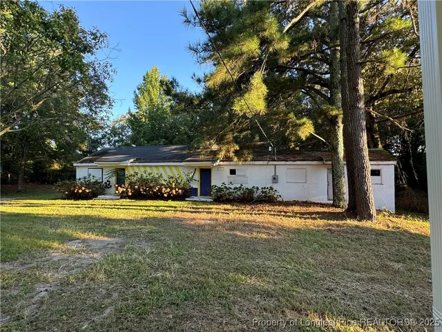 a view of a house with a yard and large tree