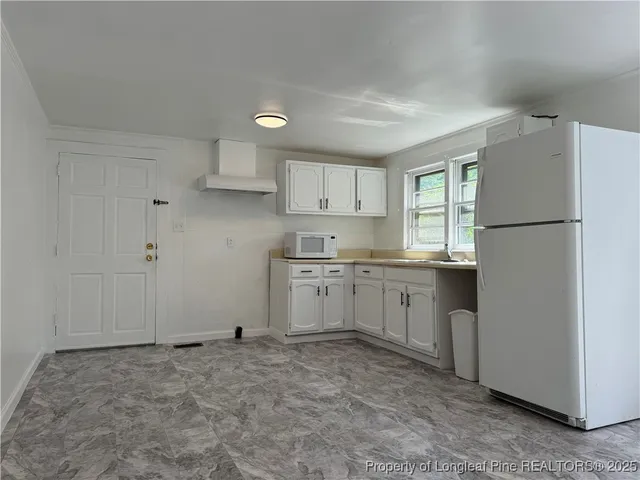 a kitchen with white cabinets and white appliances