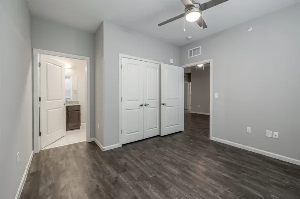 an empty room with wooden floor and ceiling fan