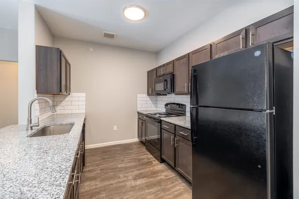 a kitchen with granite countertop stainless steel appliances a refrigerator stove top oven and sink