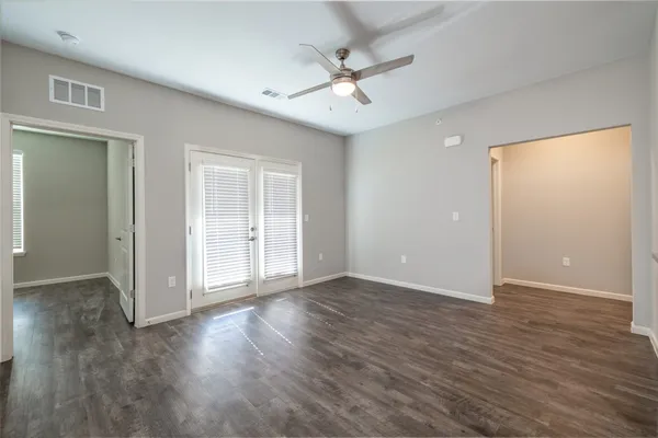 an empty room with wooden floor fan and windows